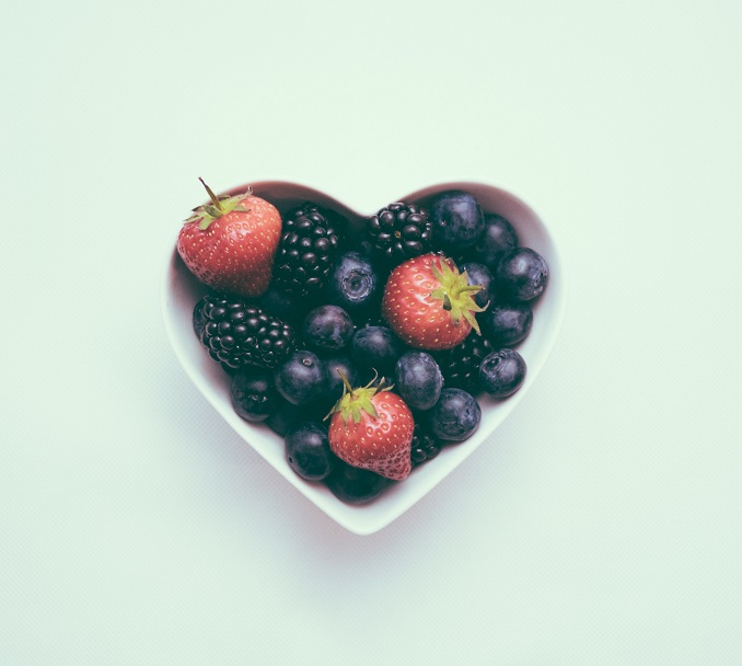 heart shaped bowl filled with strawberries, blueberries and blackberries