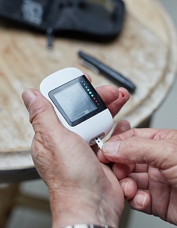 person taking their blood sugar reading using hand held monitor